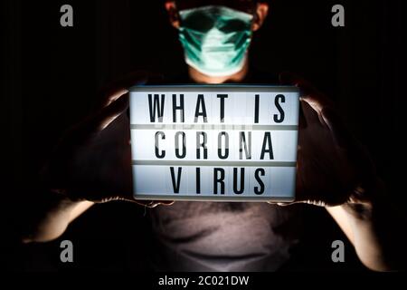 Man with protective mask hold card with text about Coronavirus disease. What is Coronavirus? 2019 - nCoV, Covid-19 virus outbreak. Stock Photo