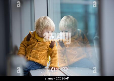 Blonde toddler boy with family, traveling with airplane, running at the airport with suitcase Stock Photo