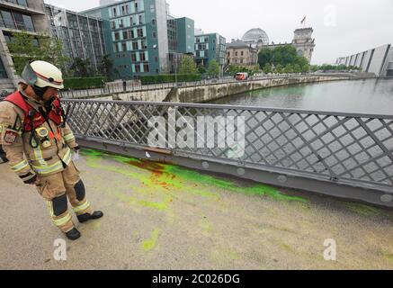 11 June 2020, Berlin: On the Marshall Bridge over the Spree River in Berlin's government district, a firefighter is standing looking at the dye uranine on the ground, which activists from Extinction Rebellion (XR) used to turn parts of the water poisonous green during the 'Coal Poisoned' campaign. The activists want to use it to draw attention to the far-reaching damage that coal mining causes to people and the environment. Credit: dpa picture alliance/Alamy Live News Stock Photo