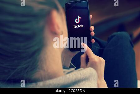 KYIV, UKRAINE-JANUARY, 2020: Tiktok on Smart Phone Screen. Young Girl Pointing or Texting Mobile Phone During a Pandemic Self-Isolation and Coronavirus Prevention. Stock Photo