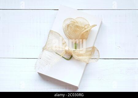 Blank papers to write letters tied with a raffia ribbon and decorated with an artificial flower on an old white wooden table Stock Photo