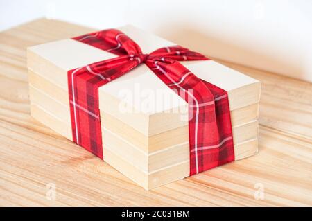 Four books tied with a  patterned ribbon with red and white squares on a wooden table. Stock Photo