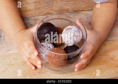 Figs energy balls in glass jar on wooden table. Holding small girl Stock Photo