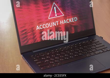 Hacked account concept on laptop screen with red background. Warning triangular sign with exclamation mark symbol. Horizontal. Stock Photo