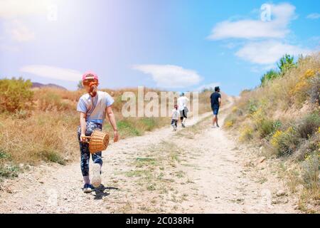 Family with three children hiking in the countryside trail to the mountains. Activities in freedom with families. Cute girl walking through a pathway Stock Photo