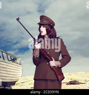 Attractive woman in army uniform carrying a rifle Stock Photo