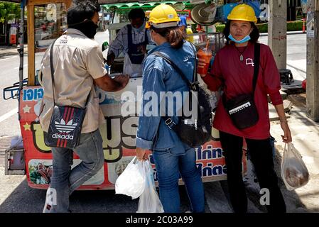 Thailand female builder wearing hardhat and buying refreshment soft drinks from a street cart. Thailand Southeast Asia Stock Photo