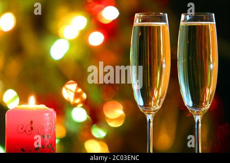 glasses with champagne and candle against festive lights Stock Photo