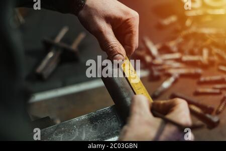 The blacksmith manually forging the molten metal on the anvil in smithy with spark fireworks. Blacksmith working on metal on anvil at forge high speed Stock Photo