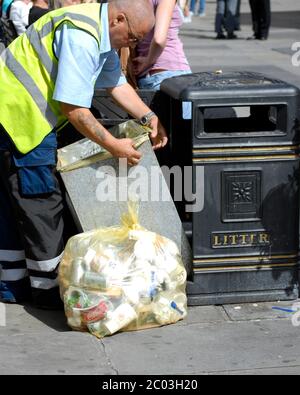 Local Authority Council worker empties public waste bin and fits new bin liner. Stock Photo