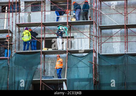 Workers on metal scaffoldings renovating the exterior of apartment building. Bucharest, Romania, 2020 Stock Photo