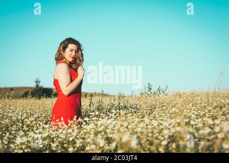 woman with red dress and poppy in hand in the field. Stock Photo