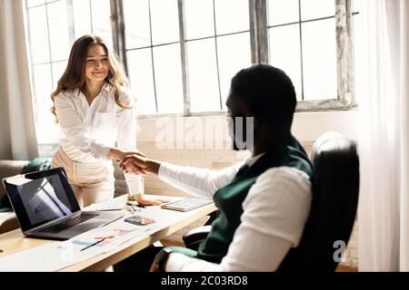 Welcome to our team. Young modern men in smart casual wear shaking hands while working in the creative office Stock Photo