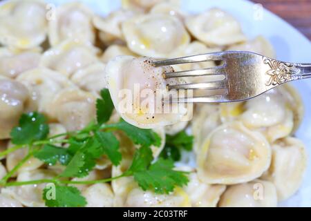 Pelmeni with sour cream, the butter ground by pepper and fresh parsley Stock Photo