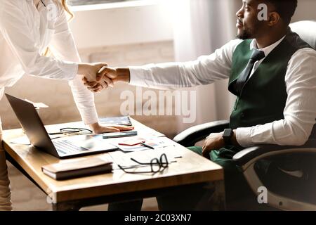 Welcome to our team. Young modern men in smart casual wear shaking hands while working in the creative office Stock Photo