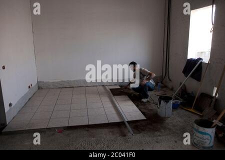Installing floor tiles in new accomodation blocks for construction and management executives for a new oil and gas facility in the Sahara desert. Stock Photo