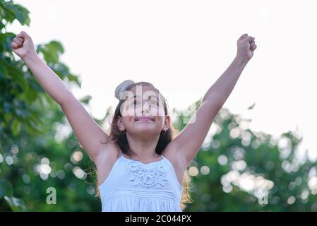 Victorious girl celebrating with her arms in the air. Success, achievement and victory concept. Stock Photo