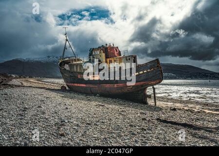 Ship wreck on the beach at low tide. The Old Boat of Corpach, Ben Navis on Loch Eil near Fort William in Scotland. Stock Photo