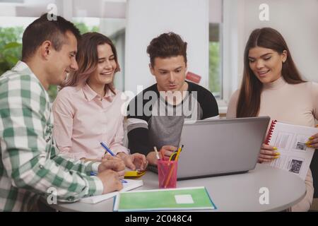 Group of college friends studying together, using laptop. Cheerful high school students browsing online on computer, working on a project Stock Photo