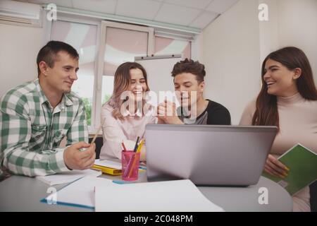 Diverse group of college friends studying together, using laptop. University students discussing their project at the classroom. Education, friendship Stock Photo