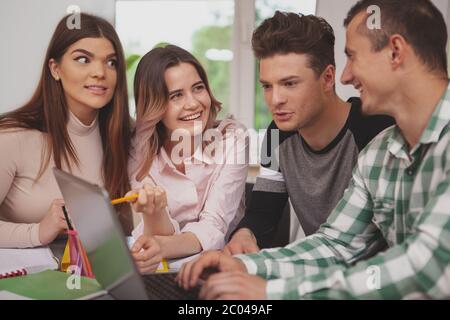 Cropped shot of happy young college students laughing, discussing their project. Beautiful young female student smiling, talking to her classmates, st Stock Photo