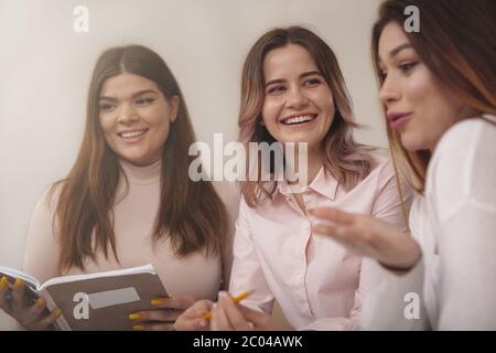 Friendship, campus life concept. Cropped shot of lovely young women studying together at college library. Attractive female students preparing for exa Stock Photo