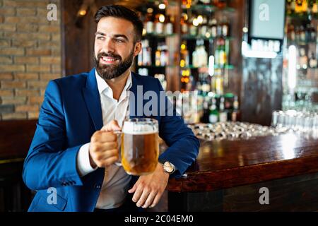 Handsome young man is drinking beer in bar and smiling Stock Photo