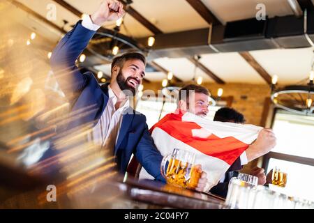 Men fans screaming and watching football on TV and drink beer in a pub Stock Photo