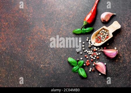 Collection of spices herbs. Ingredients for cooking. Red pepper, garlic, basil leaves, pepper corns on dark stone concrete table background. Top view. Stock Photo