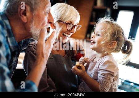 Happy smiling senior randparents playing with their granddaughter Stock Photo