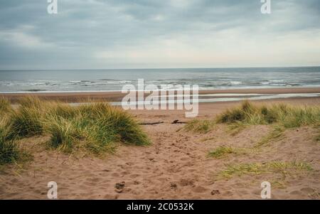 Panoramic view of St Cyrus beach with rocks, sea and house on the cliff on blue sky background. Scotland, United Kingdom. April 2019 Stock Photo