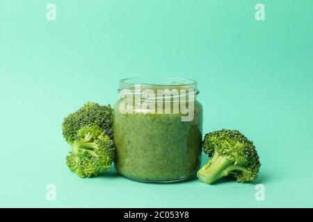 Glass jar with broccoli puree on mint background Stock Photo