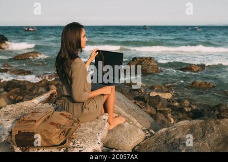 Modern technology for work. A young girl works on a laptop at sea. Work as a freelancer away from the office. Work while traveling. Successful busines Stock Photo