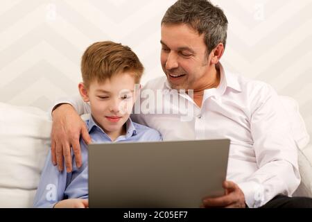 Boy and father using laptop together Stock Photo