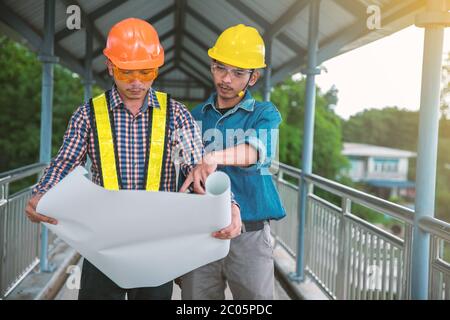 Two engineers stand hand in hand on bridge Stock Photo