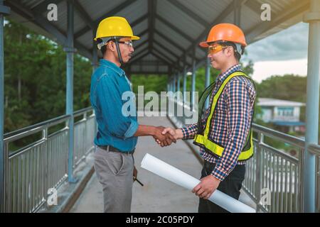 Two engineers stand hand in hand on bridge Stock Photo