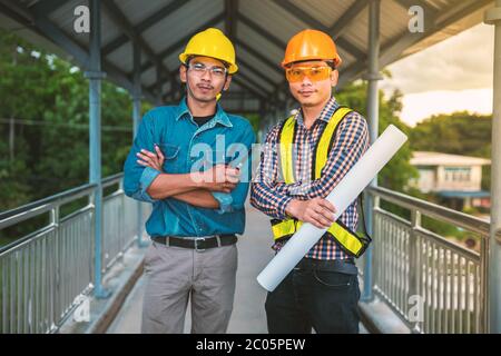 Two engineers stand hand in hand on bridge Stock Photo