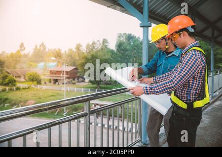 Two engineers stand hand in hand on bridge Stock Photo
