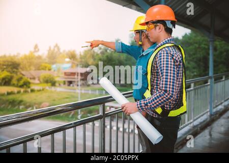 Two engineers stand hand in hand on bridge Stock Photo