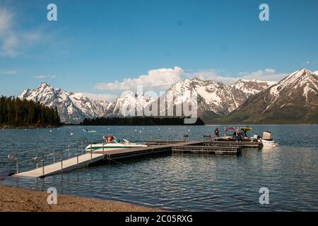 Boaters on Jackson Lake at Colter Bay with the snow capped Teton Mountain Range behind during spring at Grand Teton National Park in Moose, Wyoming. Stock Photo