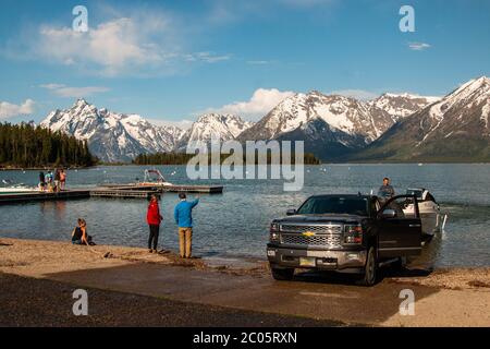 Boaters on Jackson Lake at Colter Bay with the snow capped Teton Mountain Range behind during spring at Grand Teton National Park in Moose, Wyoming. Stock Photo