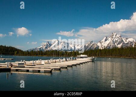 Boaters on Jackson Lake at Colter Bay with the snow capped Teton Mountain Range behind during spring at Grand Teton National Park in Moose, Wyoming. Stock Photo