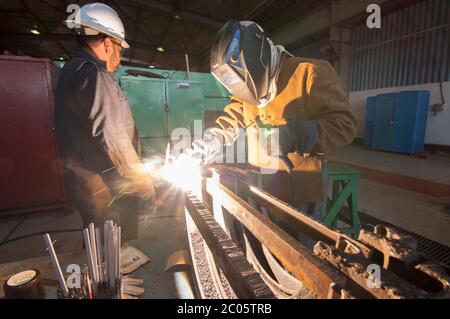 Employees in a Geothermal power plant performing welding jobs and a training program in the mechanic workshop as part of a skilled job apprentice plan. Stock Photo