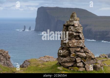 Cairns, so-called guard, Tjoernuvik or Tjornuvik, Streymoy, behind rock needles Risin og Kellingin in front of cliff Eioiskollur, Faroe Islands Stock Photo