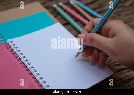 Hand holding pencil and book at wood desk background Stock Photo