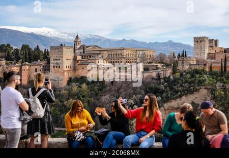 Tourists taking pictures of the Moorish city castle Alhambra, Nasrid palaces, Palace of Charles V, snow-covered Sierra Nevada in the back, Granada Stock Photo