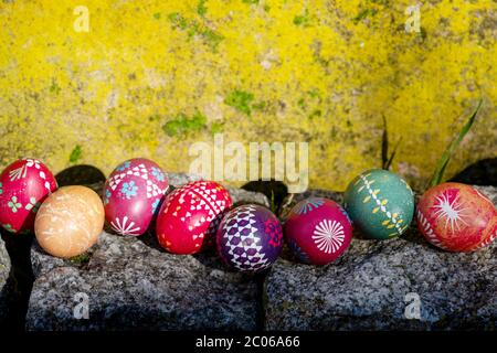 Sunny yellow wall and Stones with Easter eggs from Germany handmade with wax technique, old Eastern Germany tradition, craftsmanship, custom made east Stock Photo