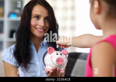 Girl throwing coin into moneybox Stock Photo