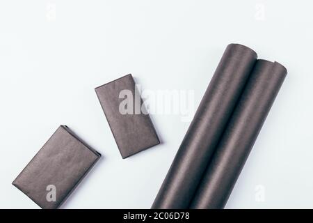 Flat lay composition roll of black paper for packing presents next to gift boxes on white background. Stock Photo