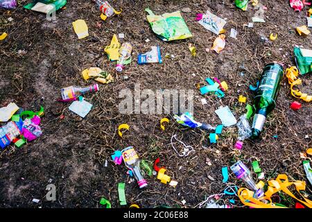 Empty beer bottles, chocolate packagings, festival decorations and other garbage are lying on the sidewalk after the traditional carnival parade. Stock Photo